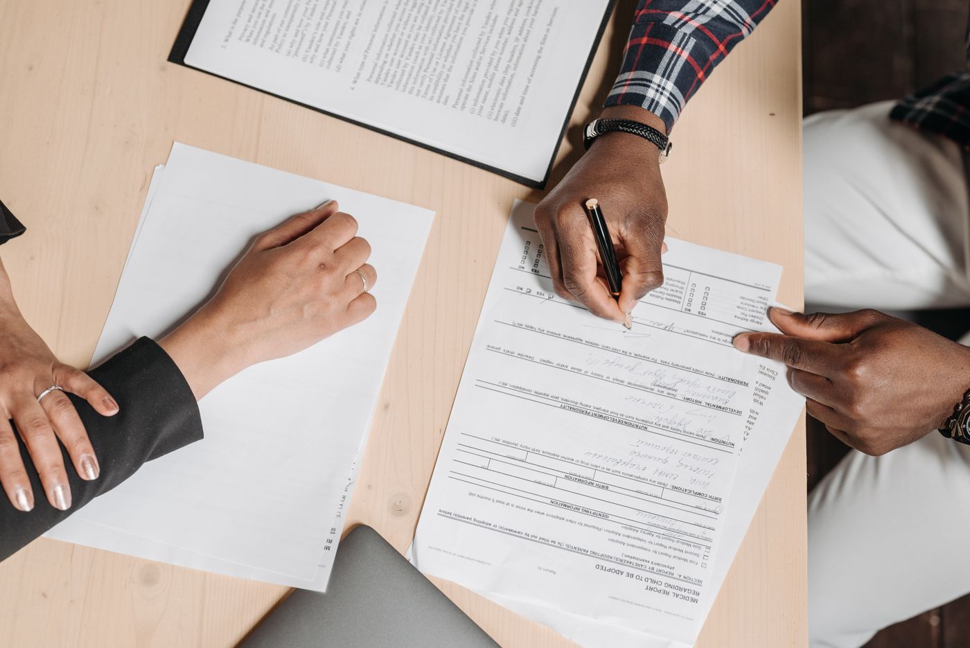 Two people carefully reviewing and signing documents at a desk