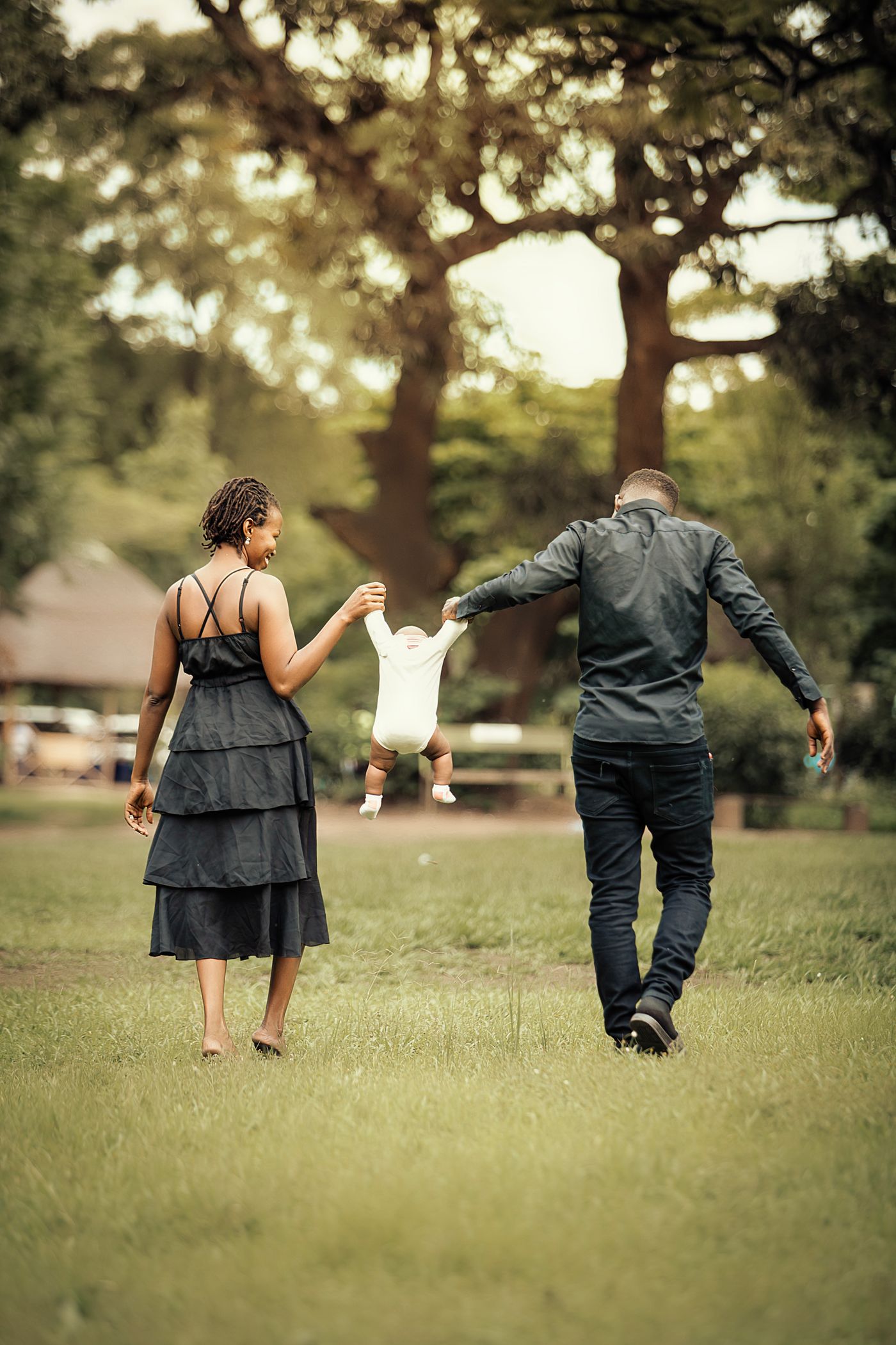 A family walking hand in hand together in a sunlit park